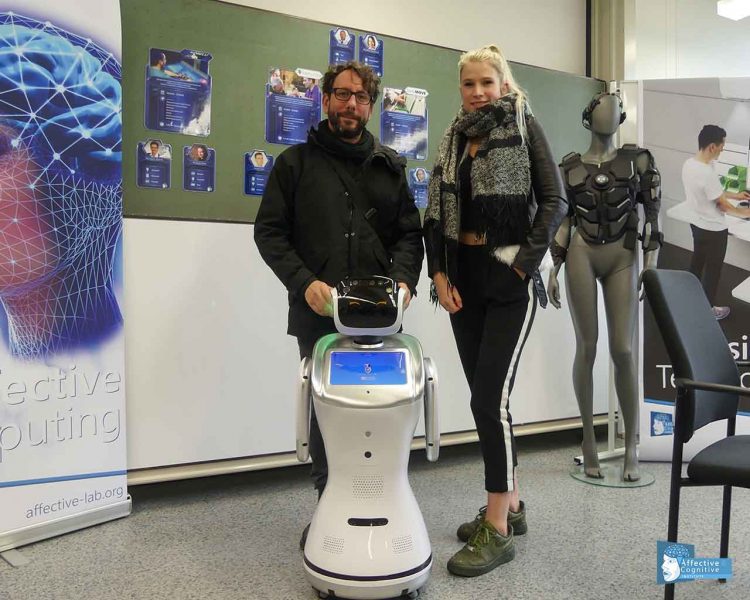 Two persons are standing together with a robot.